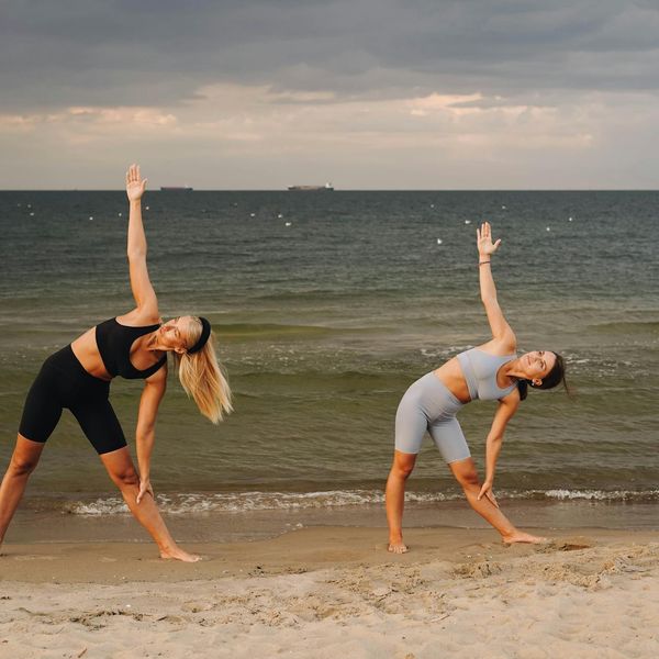Person in a dynamic yoga pose outdoors during sunset.